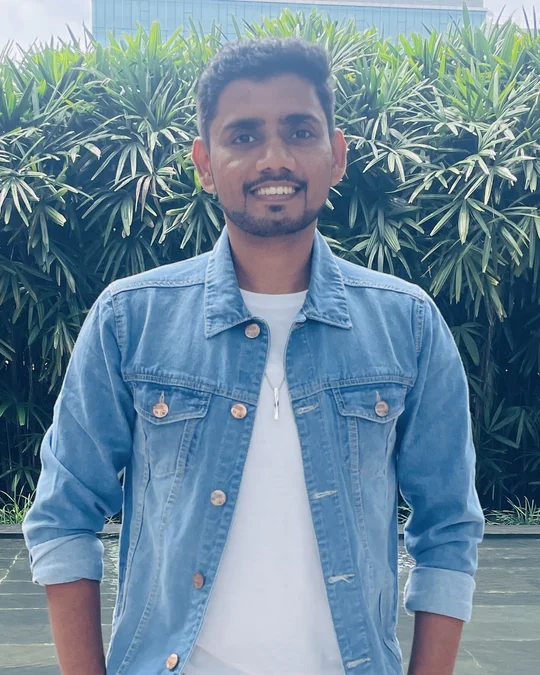 Abhishek Birdawade, founder of Start Your Channel, smiling, in a denim jacket in front of green plants.